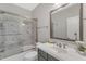 Bathroom showcasing marble countertop, framed mirror, and a shower-tub combination with glass doors at 7304 Hasentree Club Dr, Wake Forest, NC 27587