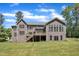Back exterior view of a home with a well-maintained lawn, a deck, and mature trees providing shade and privacy at 7304 Hasentree Club Dr, Wake Forest, NC 27587