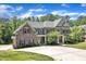 Beautiful two-story home with a stone and gray facade, a well-manicured lawn and plentiful driveway space at 7304 Hasentree Club Dr, Wake Forest, NC 27587