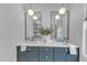 Bathroom vanity with dual sinks, dark blue cabinets, and round mirrors at 801 N Elm St, Durham, NC 27701
