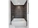 Modern bathroom with a white soaking tub, dark marbled tile, and chrome fixtures at 801 N Elm St, Durham, NC 27701