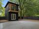 Modern backyard cottage featuring a balcony, large windows, privacy fence, and ample concrete patio space at 805 Camden Ave, Durham, NC 27701