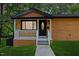 Charming cottage features a covered porch with horizontal wood siding and modern outdoor lighting at 805 Camden Ave, Durham, NC 27701