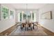 Sunlit dining room featuring a large table, neutral decor, and picturesque views of the landscaped backyard at 909 N Gregson St, Durham, NC 27701