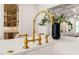 Close-up of the kitchen sink featuring gold fixtures, marble countertops, and natural lighting at 909 N Gregson St, Durham, NC 27701