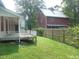 Large backyard with lush green lawn, a wood fence, mature trees and a partially covered porch at 915 Phils Creek Rd, Chapel Hill, NC 27516