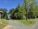 View of the property featuring gravel driveway, trees, grass, and a car with a partial view of the house at 915 Phils Creek Rd, Chapel Hill, NC 27516