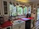 Bright kitchen features a red countertop, white cabinets, large window with plants and coffee mugs at 915 Phils Creek Rd, Chapel Hill, NC 27516