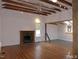 Spacious living room featuring exposed beam ceiling, fireplace, hardwood floors, and modern ceiling fan at 915 Phils Creek Rd, Chapel Hill, NC 27516
