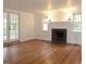 Bright living room with fireplace, wood floors, white walls, French doors, and windows with natural light at 915 Phils Creek Rd, Chapel Hill, NC 27516
