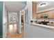 Partial view into the kitchen with wood cabinets and appliances from a light-filled hallway, showcasing an open layout at 102 Rosebrooks Dr, Cary, NC 27513