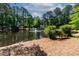 Scenic pond view with a fountain and a park bench surrounded by lush greenery and tall trees at 102 Rosebrooks Dr, Cary, NC 27513