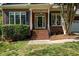 Close-up of a brick home's front entrance with well-maintained landscaping and a welcoming porch at 104 Crossway Ln, Holly Springs, NC 27540