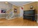 Inviting living room featuring hardwood floors, a staircase, and classic piano at 104 Crossway Ln, Holly Springs, NC 27540