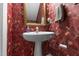 Charming powder room featuring floral wallpaper, pedestal sink, and a gold framed mirror at 104 Crossway Ln, Holly Springs, NC 27540