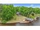 Aerial view of lake house, boat house and lawn surrounded by lush trees at 104 Pontiac Cv, Louisburg, NC 27549