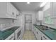 Clean kitchen with white cabinets, green countertops, and laundry area in the back at 104 Pontiac Cv, Louisburg, NC 27549