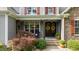 Inviting front porch showcasing decorative wreaths, colorful foliage, rocking chair, and a stylish double-door entrance at 110 Pebble Creek Dr, Franklinton, NC 27525
