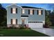 Charming two-story home with blue siding, black shutters, stone accents, and a two-car garage at 1100 Landen Creek Ln, Zebulon, NC 27597