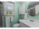 Bright bathroom featuring a mint color scheme, a round mirror, and a window with natural light at 1114 Balmoral Dr, Cary, NC 27511