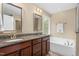Bathroom featuring double sinks, granite counters, soaking tub, and bright natural light at 114 Bell Tower Ct, Elon, NC 27244