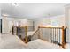 Upstairs hallway with carpet, wood and metal railing, chandelier, and natural light at 114 Bell Tower Ct, Elon, NC 27244