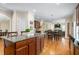 Open concept floor plan of kitchen and dining room with granite island and wood cabinets and floors at 114 Bell Tower Ct, Elon, NC 27244