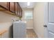 Bright laundry room features a window, overhead storage, and tile floors at 114 Bell Tower Ct, Elon, NC 27244