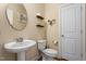 Well-lit powder room with pedestal sink, wood floors, and decorative wall shelves at 114 Bell Tower Ct, Elon, NC 27244
