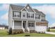 Beautiful two-story home with gray siding, a stone accent, covered entry, and a lush green lawn at 11412 International Dr, Middlesex, NC 27557