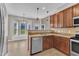 An inviting kitchen featuring stainless steel appliances and warm wood cabinets, complemented by recessed and pendant lighting at 120 Cobblebrook Ct, Holly Springs, NC 27540