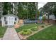Backyard view with an above ground pool, shed, brick landscaping, stone walkway, patio set and tall trees at 1213 Indian Trail Dr, Raleigh, NC 27609