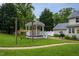 A beautifully landscaped backyard featuring a gazebo, swing set, and well-manicured lawn at 1213 Indian Trail Dr, Raleigh, NC 27609