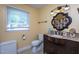 Bathroom featuring a vanity, patterned mirror, toilet, and a window for natural light at 1213 Indian Trail Dr, Raleigh, NC 27609
