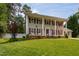 Traditional two-story home featuring white columns, green paint, red shutters, and a well manicured lawn at 1213 Indian Trail Dr, Raleigh, NC 27609