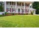 Traditional two-story home featuring white columns, green paint, red shutters, and a well manicured lawn at 1213 Indian Trail Dr, Raleigh, NC 27609