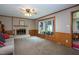 Cozy living room featuring a fireplace, large bay window, ceiling fan, and access to an enclosed porch at 1213 Indian Trail Dr, Raleigh, NC 27609