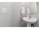 Clean half-bathroom featuring a modern vanity with pedestal sink, oval mirror, and light gray walls at 147 Antler Steel Dr, Clayton, NC 27527