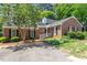 A cozy one-story brick home featuring black shutters, complemented by lush landscaping and a verdant tree at 1623 Village Glenn Dr, Raleigh, NC 27612