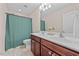 Bathroom boasts double sinks with wood cabinets and a shower with a green curtain at 1839 Huntley Way, Burlington, NC 27215