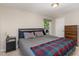Bedroom with a large bed, plaid blanket, grey sheets, two windows, and a dresser at 2029 Atkins Dr, Raleigh, NC 27610