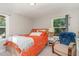 Bedroom with two windows, a bed with orange sheets, an armchair, and beige carpet at 2029 Atkins Dr, Raleigh, NC 27610