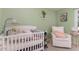 Bedroom with a crib, an armchair, hardwood floors, and soft green walls at 2029 Atkins Dr, Raleigh, NC 27610