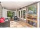 Bright sunroom with cozy wicker furniture, wood floors, and view of the outdoors through large windows and screened door at 2029 Atkins Dr, Raleigh, NC 27610