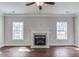 Cozy living room with a fireplace, ceiling fan, hardwood floors, recessed lights, and two large windows at 246 Pretty Run Branch Ln, Wendell, NC 27591