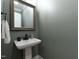 Stylish powder room with a pedestal sink, decorative mirror, and neutral paint at 2517 Medway Dr, Raleigh, NC 27608