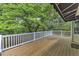 Large wooden back deck with white railing overlooking wooded backyard with lush trees and green lawn at 2608 Knightwood Rd, Fuquay Varina, NC 27526