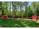 View of red barn in wooded area with tall trees and open grassy space, on sunny day at 3005 Buckhorn Rd, Sanford, NC 27330