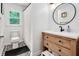 This bathroom features a modern vanity with a round mirror and black and white patterned flooring at 318 Hepowil Trce, Hillsborough, NC 27278