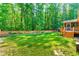 View of the spacious backyard with a wood fence, mature trees, and a deck with stairs at 33 Carrington Cir, Angier, NC 27501